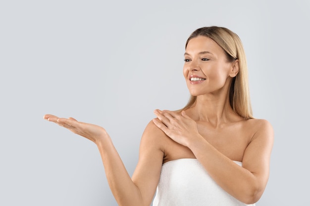 Vrolijke aantrekkelijke blonde vrouw die iets op haar hand laat zien