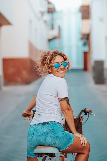 Vrolijke actieve vrouw fietsen in de straat stad en terugkijkend glimlachend Groen vervoer en actieve gezonde levensstijl mensen Vrouw geniet van fiets in stadsvervoer concept levensstijl