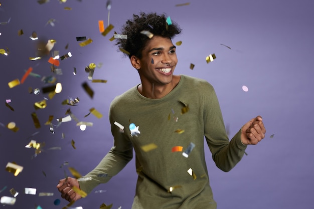 Vrolijke afro-amerikaanse jongeman dansen met gouden confetti portret lachen en lachende transgender