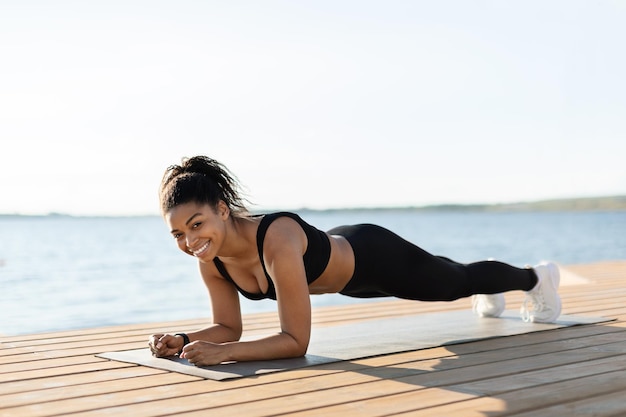 Vrolijke Afro-Amerikaanse vrouw die aan het trainen is aan zee