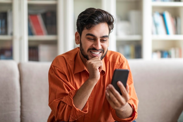 Vrolijke arabische man die thuis een telefoon gebruikt om met dames te chatten