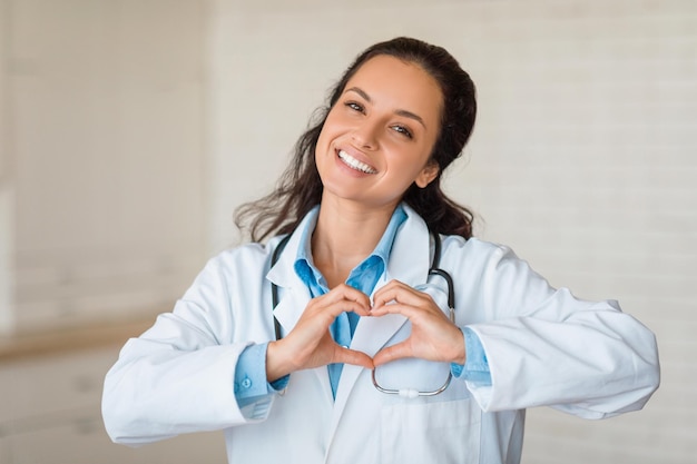 Foto vrolijke arts die hartvorm maakt met handen die glimlachen naar de camera