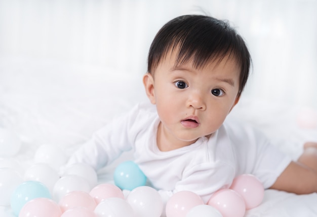 Vrolijke baby het spelen kleurenbal op bed