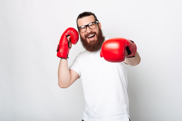 Vrolijke bebaarde hipster man in casual ponsen met rode bokshandschoenen