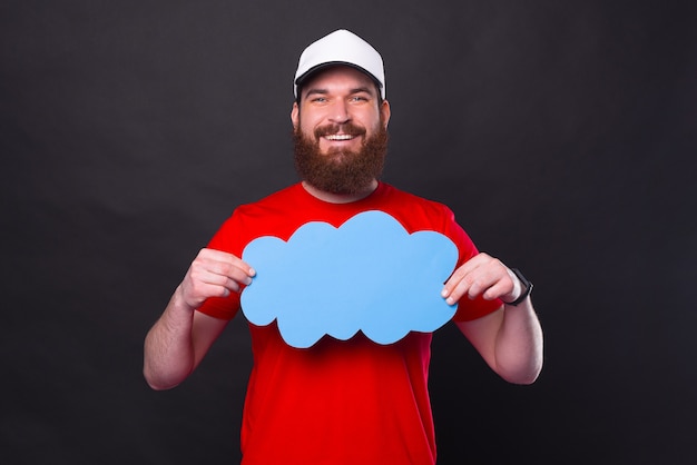 Vrolijke bebaarde hipster man in rood t-shirt met lege blauwe toespraak wolk