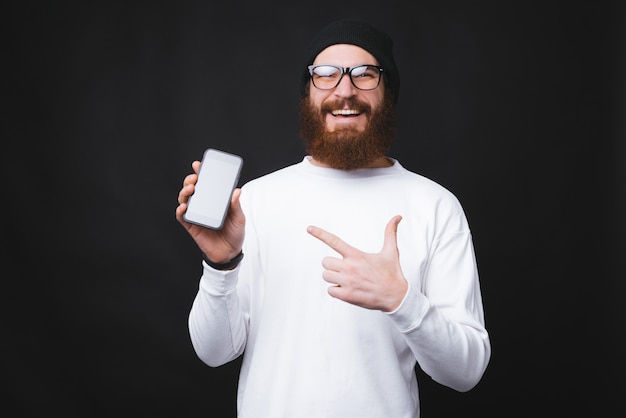 Vrolijke bebaarde hipster man wijzend op telefoonscherm