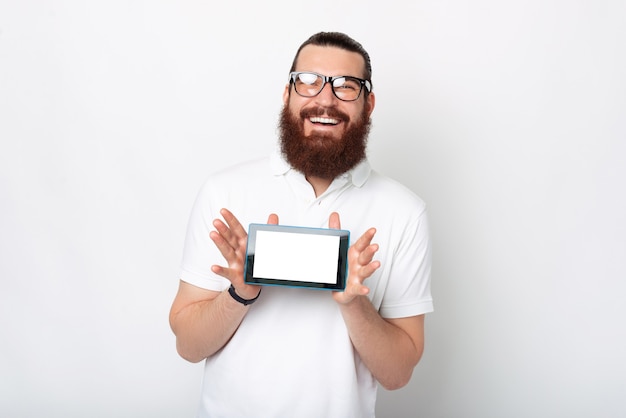 Vrolijke bebaarde man toont zijn tabletscherm aan de camera.