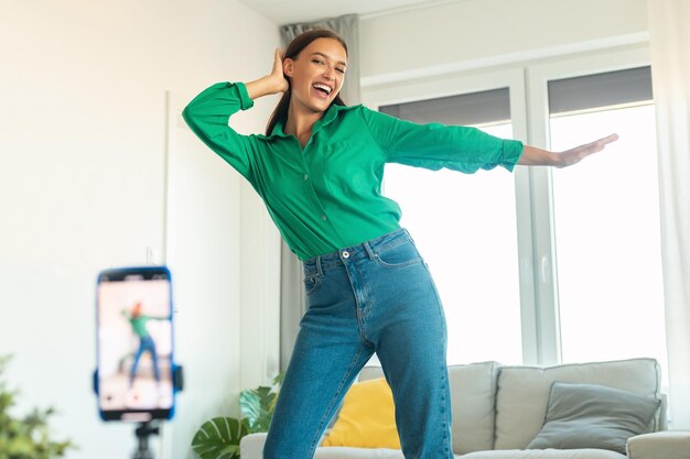 Vrolijke bloggervrouw die thuis dansvideo maakt