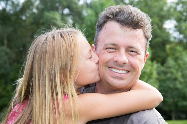 Vrolijke blonde dochter probeert haar vader te kussen