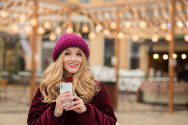 Vrolijke blonde vrouw met een mobiele telefoon, staande bij de slinger in Kiev