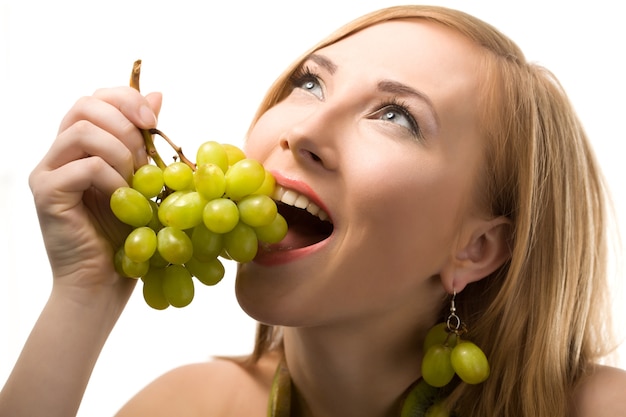 Vrolijke blonde vrouw met kort haar poseren met groene rijpe druif in handen