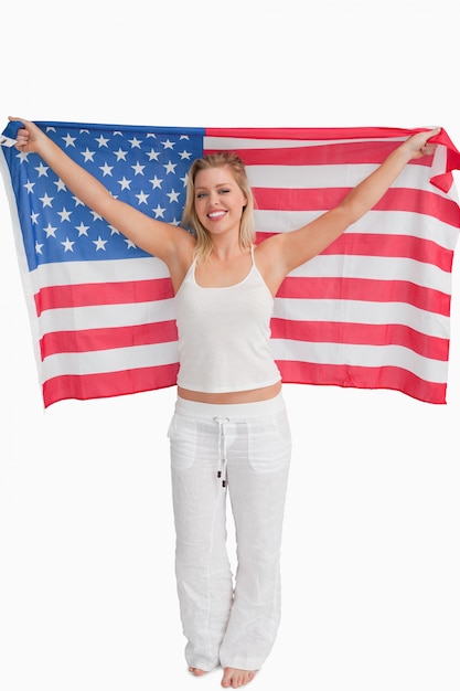 Vrolijke blondevrouw die de Amerikaanse vlag opheft