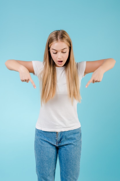 Vrolijke blondevrouw die vingers richten neer geïsoleerd over blauw