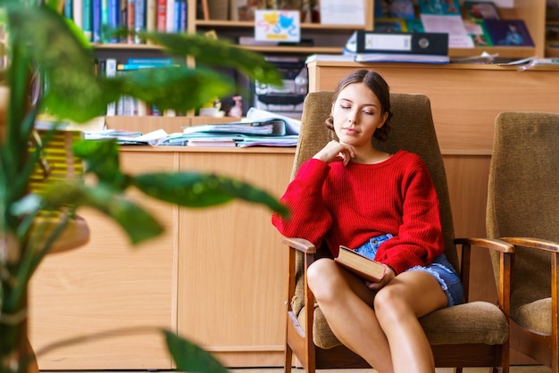 Vrolijke brunette jonge vrouw die lacht om grappig verhaal uit boek happy