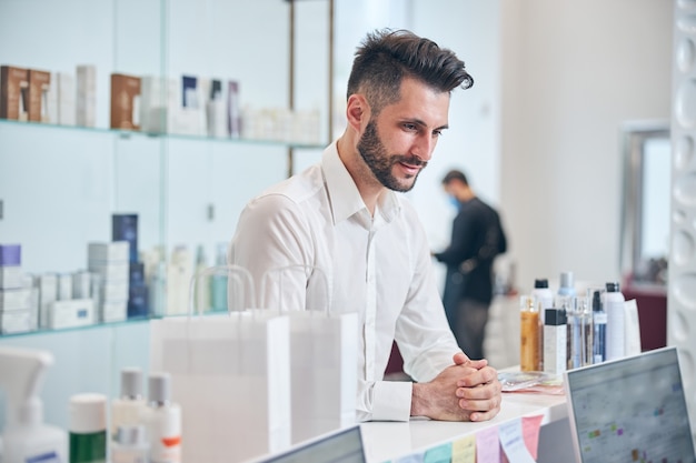 Vrolijke brunette man hand in hand terwijl hij in alle oren zit tijdens een gesprek