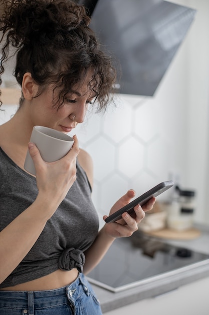 Vrolijke brunette vrouw chatten surfen internet gebruiken smartphone genieten van koffiepauze in café