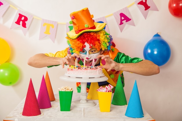 Vrolijke clownjongen op vakantie met een cake