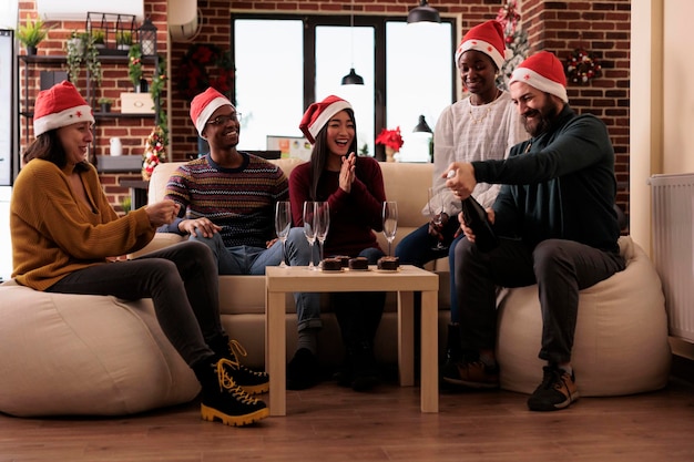 Vrolijke collega's die wijn drinken op kerstfeest, alcohol in glazen gieten om het winterfeest op de werkplek te vieren met kerstversieringen en feestelijke ornamenten.