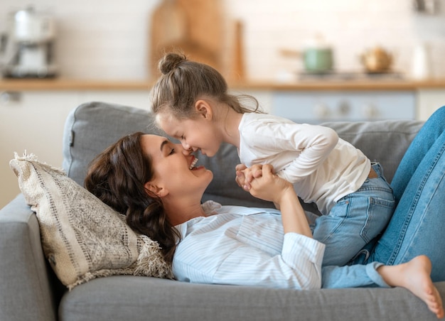 Vrolijke dag! Moeder en haar dochterkindmeisje spelen, glimlachen en knuffelen. Familie vakantie en samenzijn.