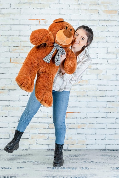 Vrolijke dame knuffelen teddybeer en glimlachen naar de camera Foto van hoge kwaliteit