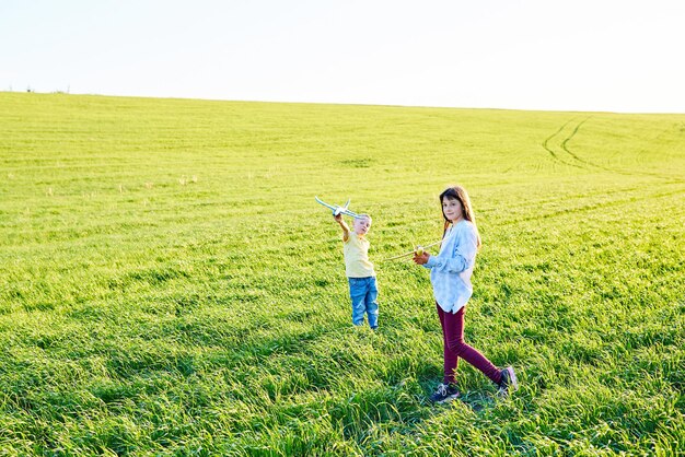 Vrolijke en blije kinderen spelen in het veld en zien zichzelf als piloot op een zonnige zomerdag Kinderen dromen van vliegen en luchtvaart