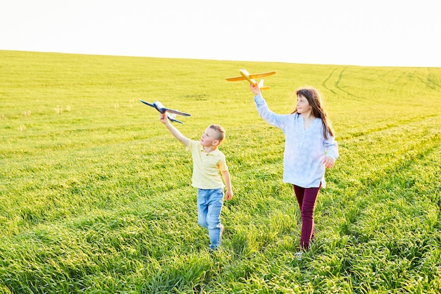 Vrolijke en blije kinderen spelen in het veld en zien zichzelf als piloot op een zonnige zomerdag Kinderen dromen van vliegen en luchtvaart