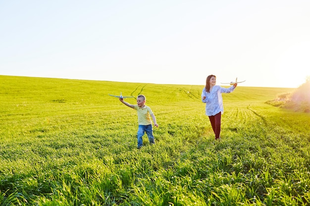 Vrolijke en blije kinderen spelen in het veld en zien zichzelf als piloot op een zonnige zomerdag Kinderen dromen van vliegen en luchtvaart