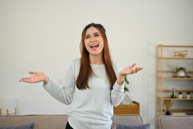 Vrolijke en gelukkige Aziatische vrouw die een geweldige tijd heeft met lachen en dansen in haar woonkamer