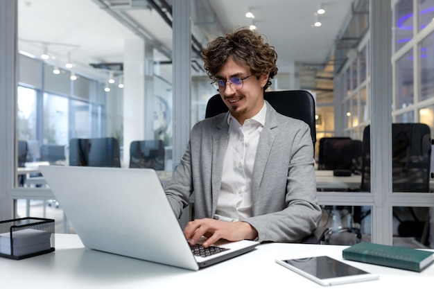 Vrolijke en succesvolle zakenman binnen kantoor werken met laptop bebaarde man glimlachend en typen