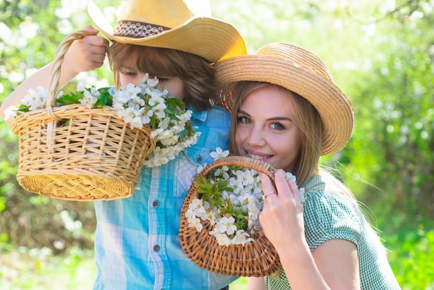 Vrolijke familie snuiven bloemenmand in park moeder met zoon samen in de tuin