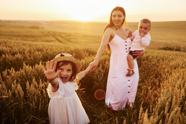 Vrolijke familie van moeder zoontje en dochter die vrije tijd op het veld doorbrengen op zonnige dagtijd van de zomer