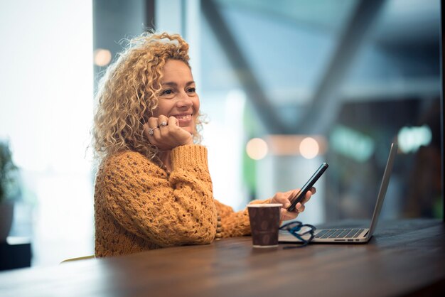 Vrolijke gelukkige mensenvrouwenreiziger wacht bij de luchthavenpoort voor een vertraagde vlucht met behulp van een modern technologisch apparaat als telefoon en laptopcomputer