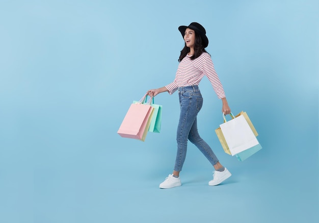 Vrolijke gelukkige tiener aziatische vrouw die geniet van winkelen, ze draagt boodschappentassen