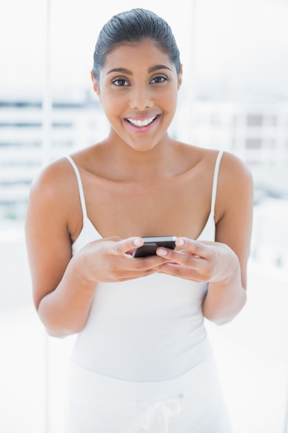 Vrolijke gestemde brunette die mobiele telefoon houdt