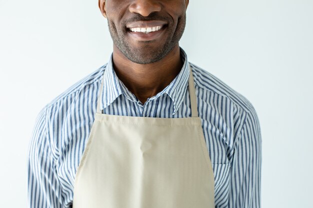 Vrolijke glimlachende afro Amerikaanse barista die zich tegen witte muur bevindt