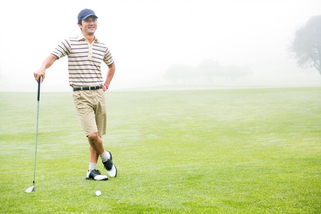 Vrolijke golfspeler die zijn club met hand op heup houdt