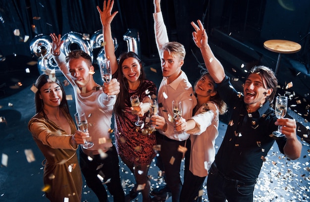 Vrolijke groep mensen met drankjes in handen die het nieuwe 2021-jaar vieren.