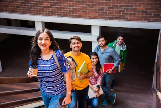 Vrolijke Indiase Aziatische jonge groep studenten of vrienden die in de campusgang of op trappen lopen