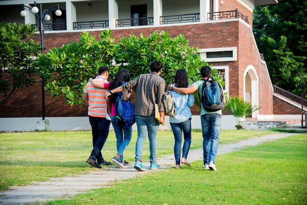 Vrolijke Indiase Aziatische jonge groep studenten of vrienden die samen lachen terwijl ze op de campus zitten, staan of lopen