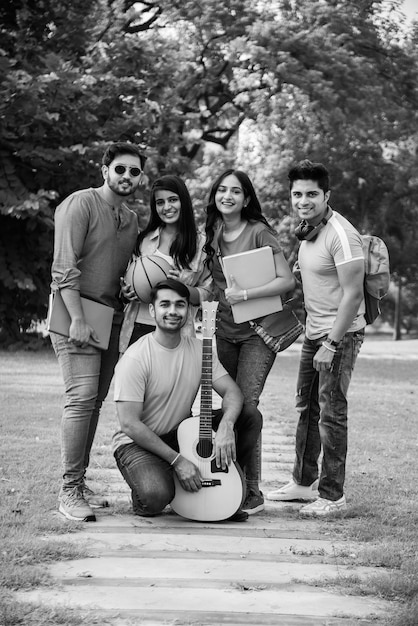 Vrolijke indiase aziatische jonge groep studenten of vrienden die samen lachen terwijl ze op de campus zitten, staan of lopen