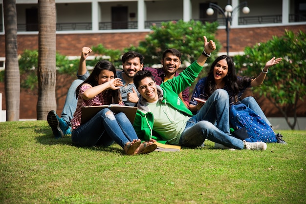 Vrolijke Indiase Aziatische jonge groep studenten of vrienden die samen lachen terwijl ze op de campus zitten, staan of lopen