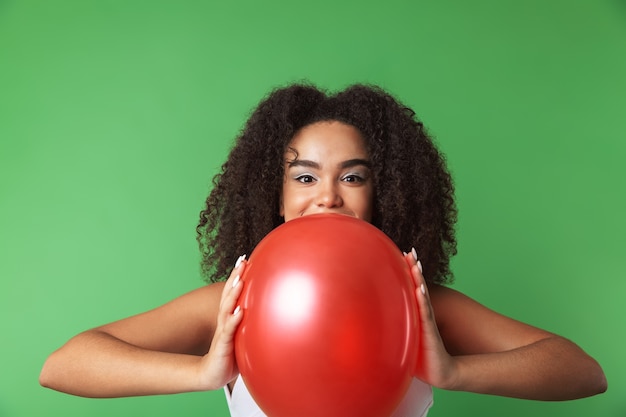 Vrolijke jonge Afrikaanse vrouw, gekleed in jurk vieren, ballon geïsoleerd te houden