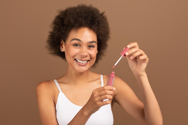 Vrolijke jonge afro-amerikaanse krullende vrouw met perfecte huid in witte borstel en lipgloss