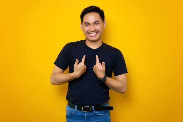 Vrolijke jonge Aziatische man in casual tshirt wijzend op zichzelf met trots geïsoleerd op gele achtergrond Mensen lifestyle concept