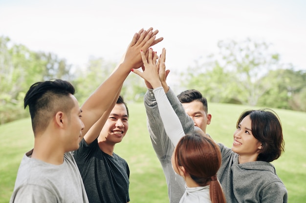 Vrolijke jonge aziatische mensen geven elkaar high five na het beëindigen van hun training buitenshuis