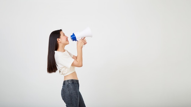 Vrolijke jonge Aziatische vrouw met megafoonaankondiging in geïsoleerde studio