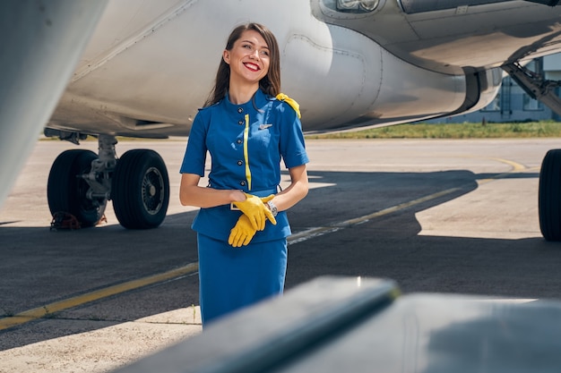 vrolijke jonge blanke dame in uniform van een stewardess die wegkijkt