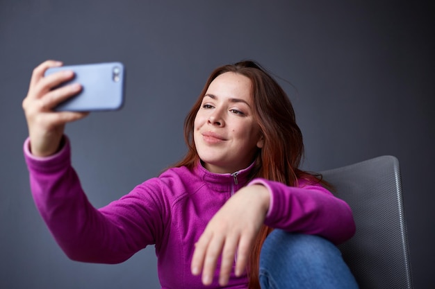 Vrolijke jonge blanke vrouw die selfie maakt Grijze achtergrond