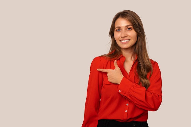 Vrolijke jonge blonde vrouw die een rood shirt draagt, wijst opzij naar de kopieerruimte