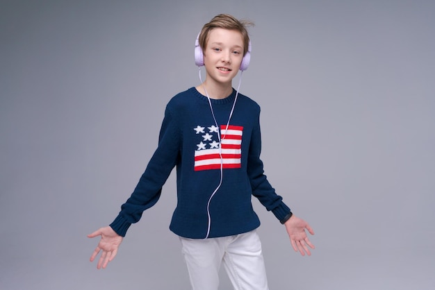 Vrolijke jonge man in blauwe trui met vlag amerika staat luisteren naar muziek op koptelefoon maakt verschil...